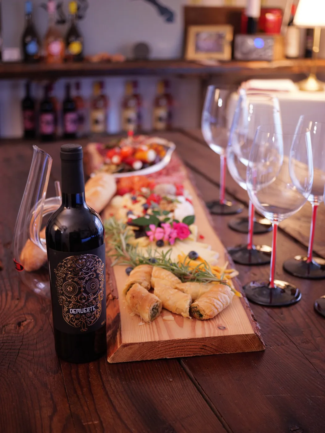 Weinprobe bei Vino Brothers: Rotweinflasche, Gläser und ein Holzbrett mit Antipasti auf der Theke